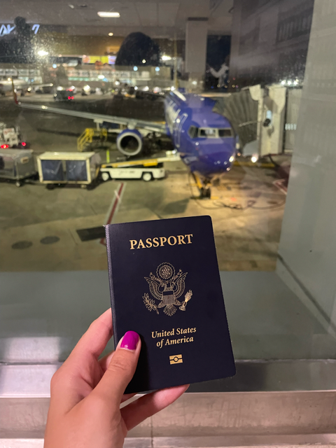 A US passport held in front of a plane at the airport